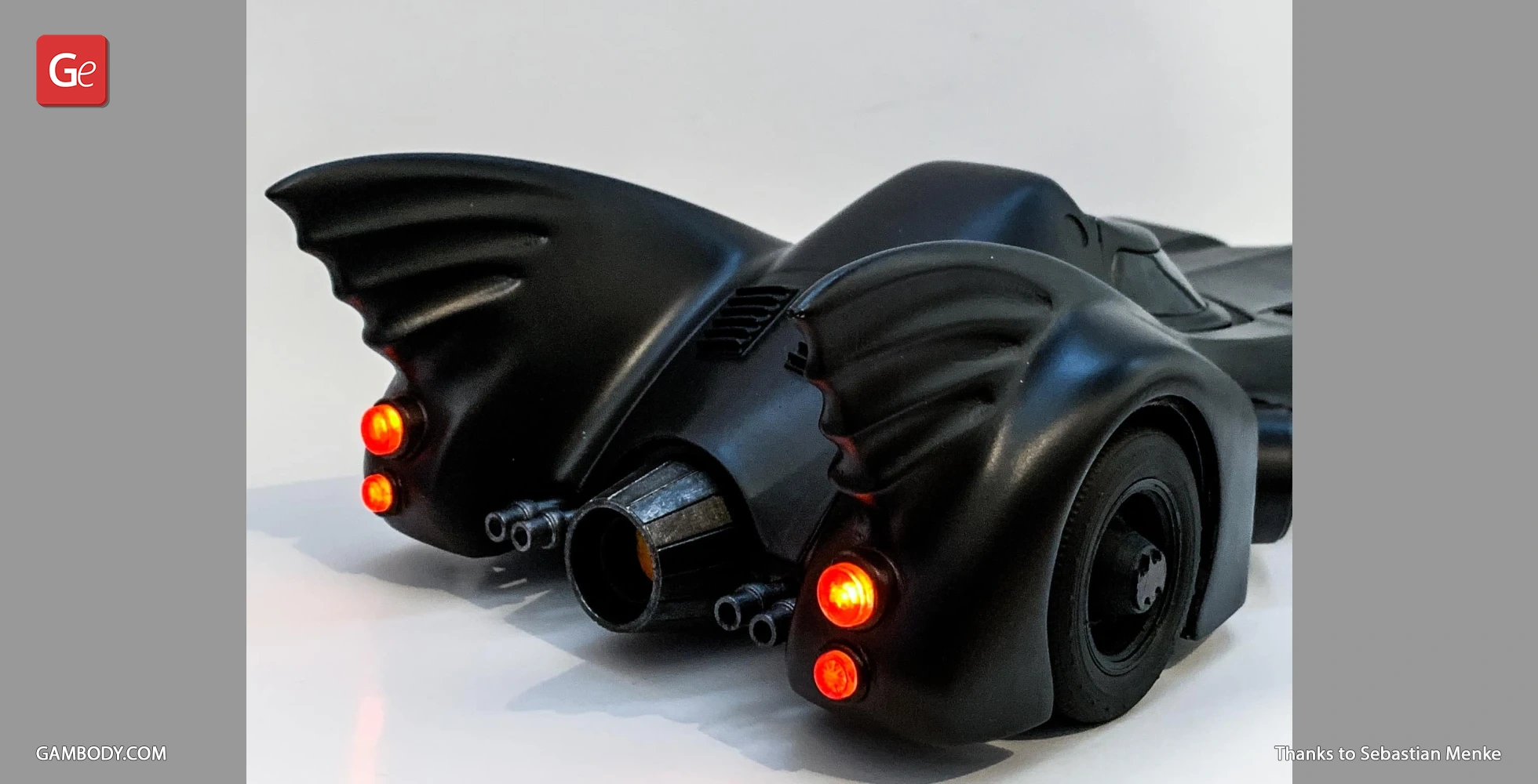 Rear view of a 3D-printed 1989 Batmobile with distinctive fins and glowing red taillights.