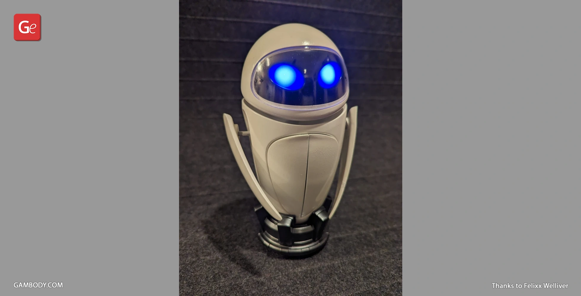 A 3D-printed EVE model with glowing blue eyes and sleek, rounded design on a dark background.